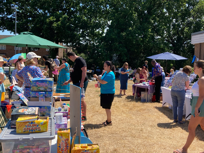 People browsing stalls at a summer fete on a sunny day.