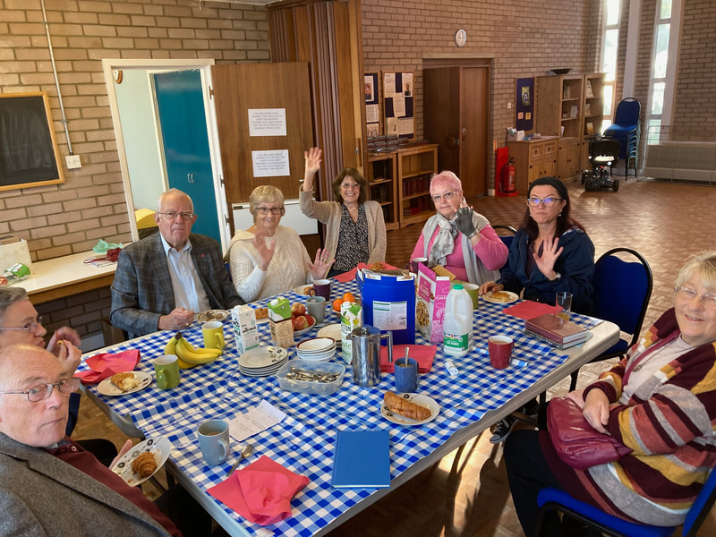 A group of church members sitting round a large table for breakfast before the church service starts.  